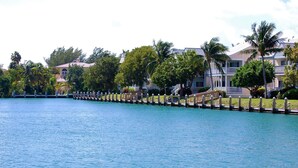 A waterfront property with a wooden dock, palm trees, and buildings with balconies. - September dates w/last minute booking discount, w/Cabana Club Access Included! (Marathon)