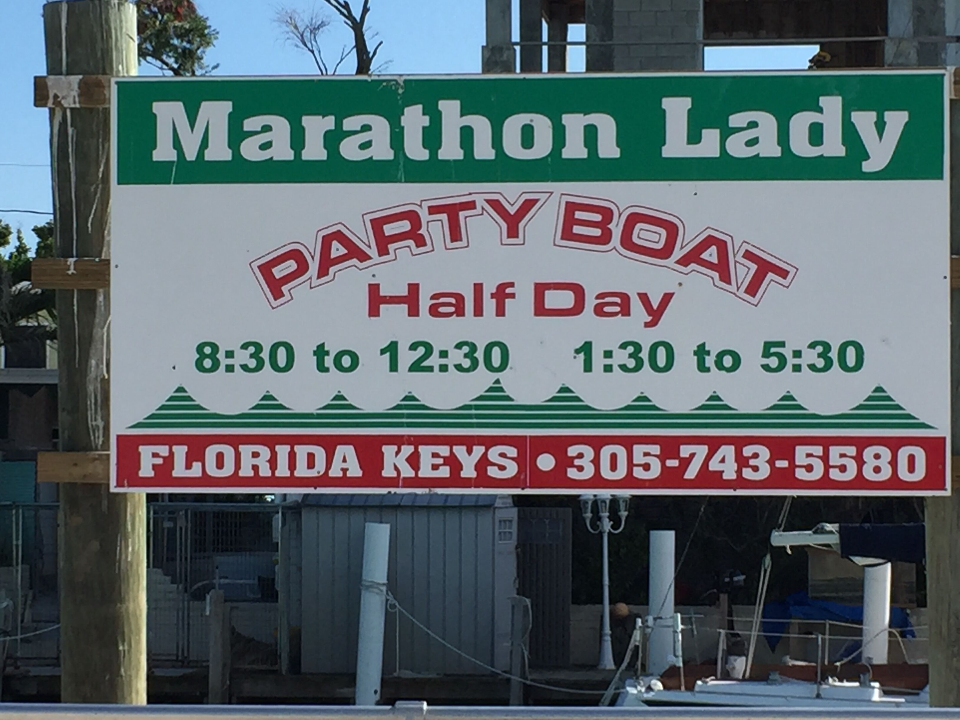 A sign for Marathon Lady, a party boat service, with operating hours and a contact number.