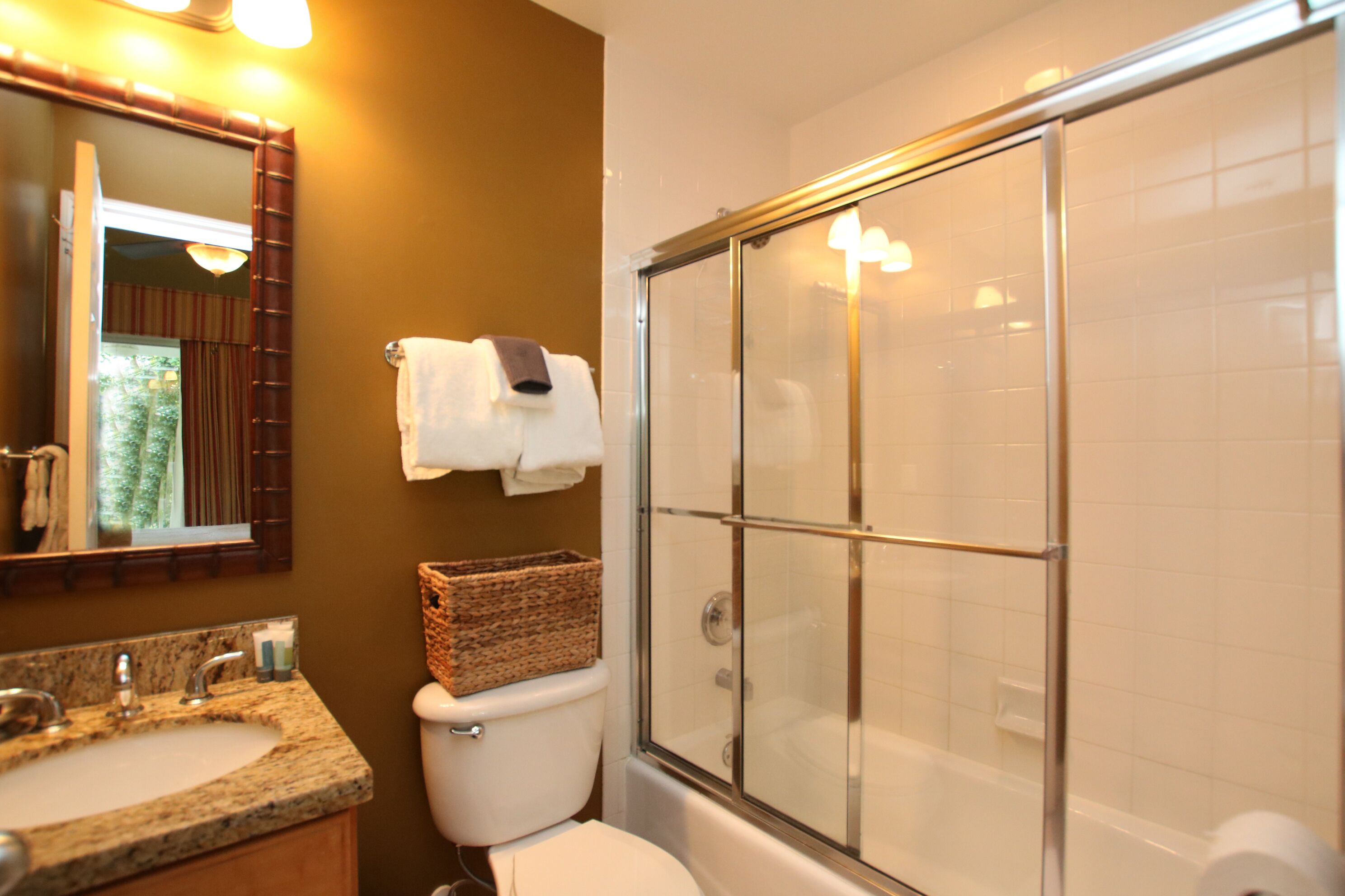 Une salle de bain équipée d’un lavabo, d’un miroir, de toilettes et d’une douche à parois de verre.