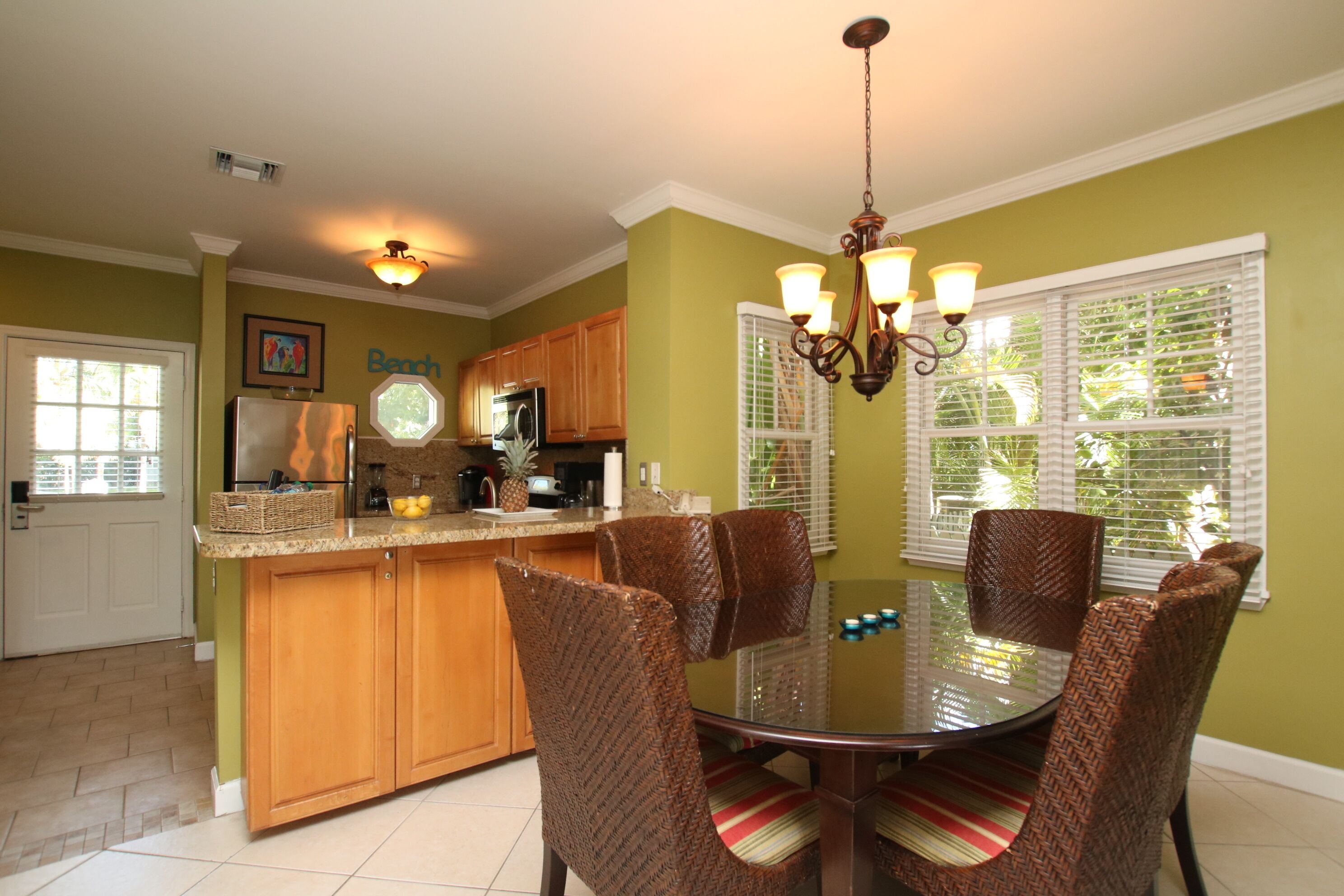 A kitchen with a dining table and chairs, wooden cabinets, a refrigerator, and a chandelier.