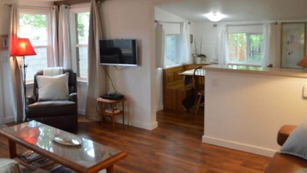 A living room with a sofa, a coffee table, a TV, and a dining area with a table and chairs. - Casita (Prescott)