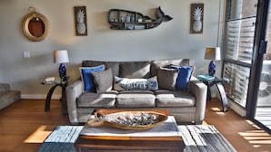 Ein Wohnzimmer mit grauem Sofa, einem Holztisch und einer Wandregal mit Dekoration.