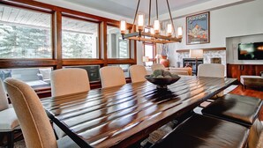 Un comedor moderno con una mesa de madera, sillas acolchadas y una lámpara colgante.