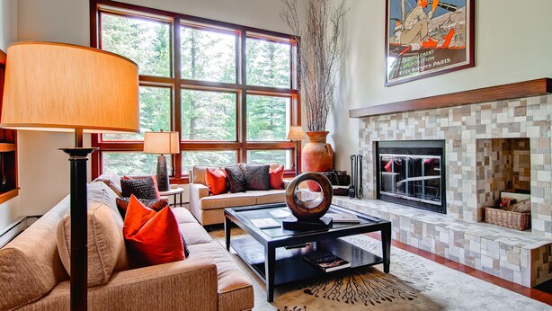 Una sala de estar con sofá, mesa de centro, chimenea y ventanas amplias.