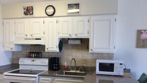 A kitchen with white cabinets, a stove, a coffee maker, a sink, and a microwave. - Beachfront II Condos. Affordable Get-Away with Public Beach Access! (Santa Rosa Beach)