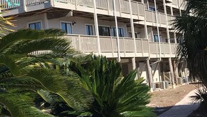 A multi-story hotel with balconies, palm trees, and a clear blue sky. - Beachfront II Condos. Affordable Get-Away with Public Beach Access! (Santa Rosa Beach)