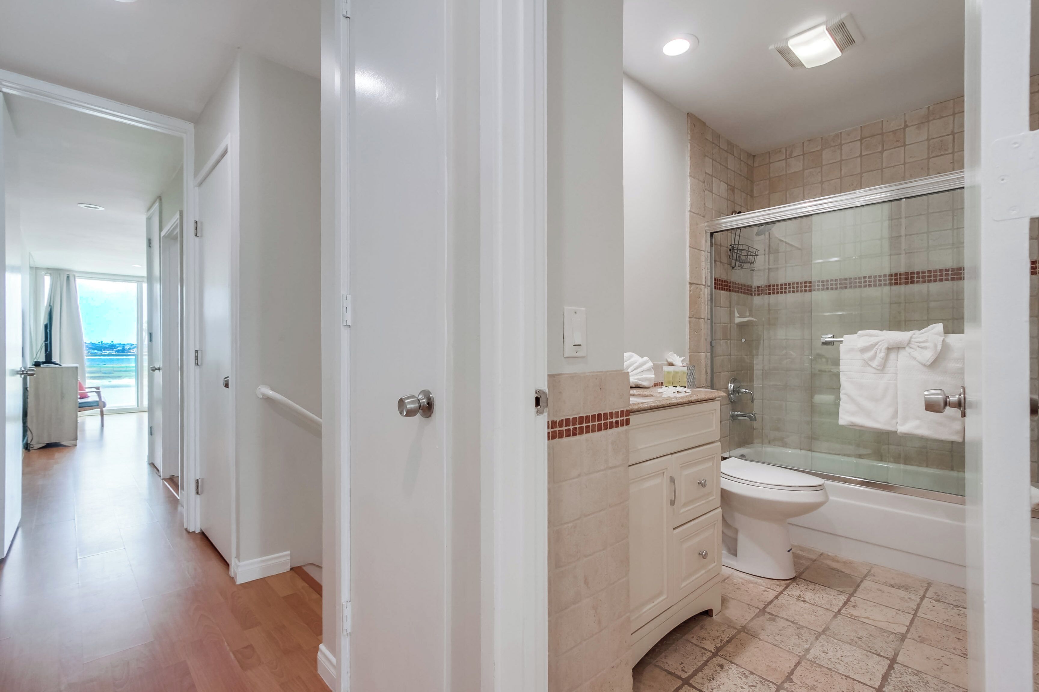 Un baño moderno con ducha de vidrio, inodoro blanco y piso de baldosas color crema.