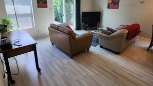 A living room with two sofas, a TV, and a table with electronic devices.