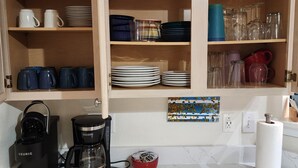 A kitchen with wooden cabinets, a coffee maker, and various dishes and cups.
