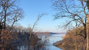 A pathway leading to a lake surrounded by leafless trees and a clear sky.
