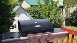 Un barbecue Thermos noir, doté de quatre boutons, posé sur une terrasse rouge.