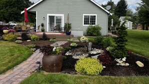 A house with a covered patio, a garden with various plants and a pathway, and a satellite dish on the roof. - Country escape next to town for a quaint cottage getaway & majestic Rainer view (Yelm)