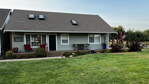 A single-story house with a front porch, a small garden, and a flag. - Country escape next to town for a quaint cottage getaway & majestic Rainer view (Yelm)