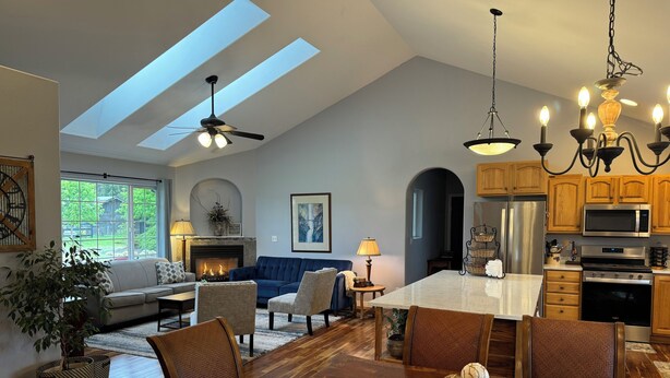 A spacious living room with a fireplace, a dining area with a large table, and a kitchen with modern appliances. - Country escape next to town for a quaint cottage getaway & majestic Rainer view (Yelm)