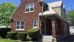 A two-story brick house with a gabled roof, a front porch, and a small attached garage. - West Inn on Weston - Great for Families (Niagara Falls)