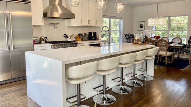 A modern kitchen with a large island, stainless steel appliances, and pendant lighting.