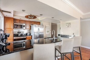 Una cocina moderna con armarios de madera, electrodomésticos de acero inoxidable y una isla central con taburetes de bar.