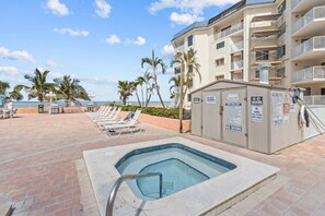 A pool area with lounge chairs, a hot tub, and a building with multiple balconies. - PICTURE PERFECT!  3 balconies! BC #2406 (Indian Shores)