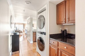 A kitchen with wooden cabinets, a black countertop, and a built-in washer and dryer.