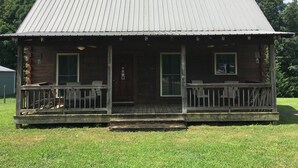 A wooden cabin with a metal roof, a porch with railings, and a door marked "HUS". - Lake Lovers Lodge Dale Hollow Lake Allons TN Near Willow Grove/Lily Dale Resorts (Allons)