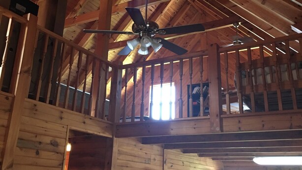 A high-ceilinged wooden cabin with a central ceiling fan, a balcony, and a kitchen area with cabinets. - Lake Lovers Lodge Dale Hollow Lake Allons TN Near Willow Grove/Lily Dale Resorts (Allons)