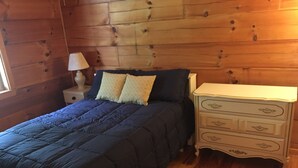 A wooden-paneled room with a bed, a nightstand, and a dresser. - Lake Lovers Lodge Dale Hollow Lake Allons TN Near Willow Grove/Lily Dale Resorts (Allons)