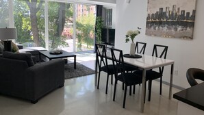 Un salon moderne avec un canapé, une table à manger et des chaises, un téléviseur et un tableau accroché au mur.