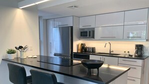 Une cuisine moderne dotée d’un îlot central, d’appareils électroménagers en acier inoxydable et de tabourets de bar.