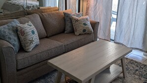 A living room with a sofa, a coffee table, and a lamp. - Beautiful Gulf Front Unit with Balcony (Gulf Shores)