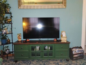A television on a wooden cabinet against a blue wall.