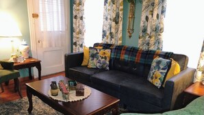 Un salon avec un canapé foncé, un fauteuil vert et une table basse en bois agrémentée d’objets décoratifs.