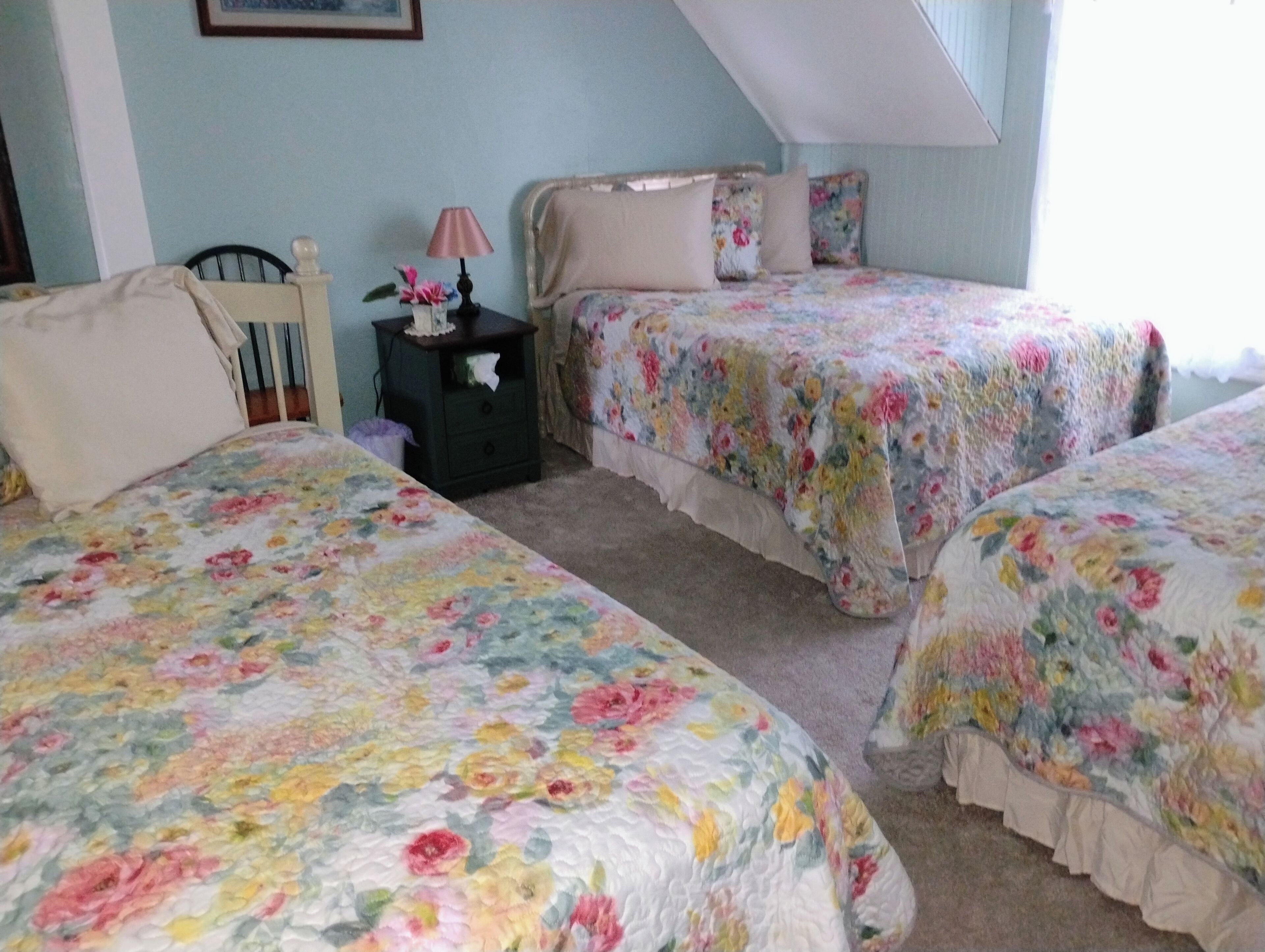 Une chambre avec deux lits, une table de chevet et une lampe.