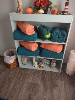 Een houten plank met netjes opgevouwen handdoeken in blauw en oranje.