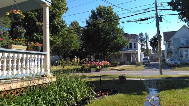 Une rue résidentielle bordée de maisons, un jardin fleuri et un petit ruisseau.