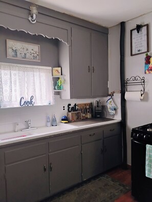 A kitchen with grey cabinets, a white countertop, a sink, and a stove.