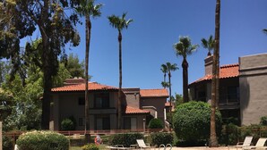 A swimming pool with clear blue water, surrounded by palm trees and a building with a red-tiled roof. - Stunning,  2 Bedroom Condo In Central Scottsdale at McCormick Ranch. (Scottsdale)