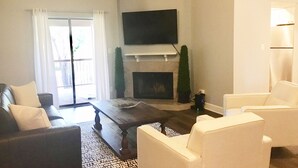 A living room with a fireplace, a flat-screen TV, and a large window with curtains. - Stunning,  2 Bedroom Condo In Central Scottsdale at McCormick Ranch. (Scottsdale)