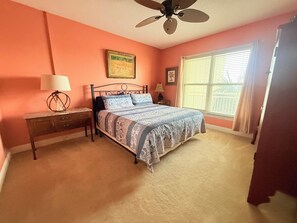 Un dormitorio con cama, mesita de noche, lámpara y ventilador de techo.