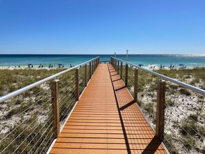 A wooden boardwalk leading to a beach with a clear blue sky.