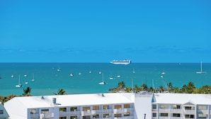 A coastal hotel with multiple balconies overlooking the sea, a cruise ship in the distance, and numerous sailboats. - Ocean Views 14A (Airlie Beach)