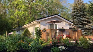 Une petite maison avec une terrasse en bois et un jardin à l’avant.