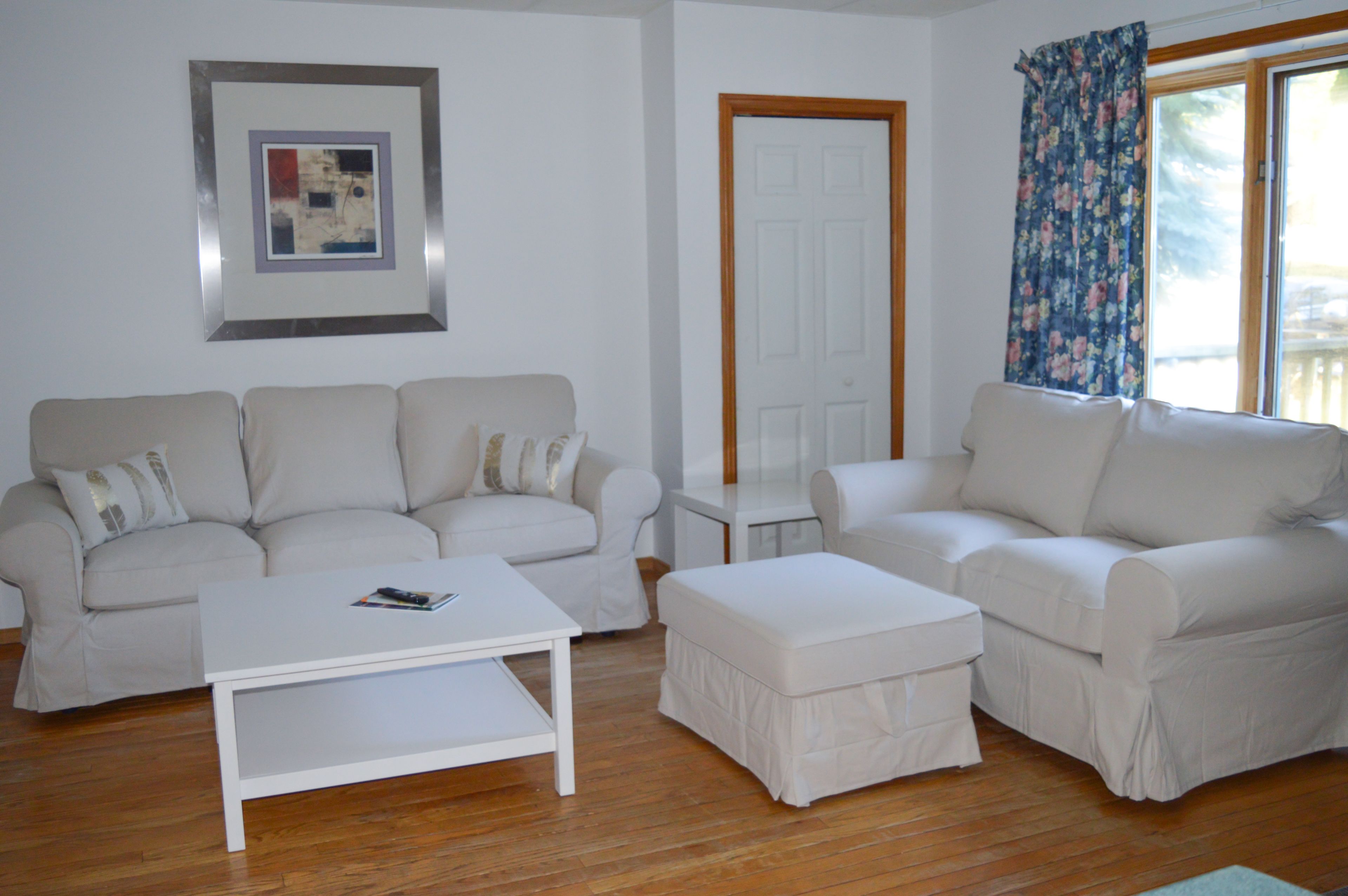 Ein Wohnzimmer mit zwei weißen Sofas, einem weißen Couchtisch und einem kleinen weißen Beistelltisch.