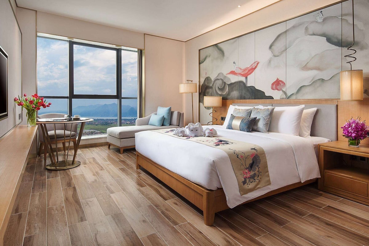 Een moderne hotelkamer met een groot bed, een bureau en uitzicht op de stad.