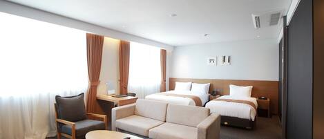 Una habitación de hotel con cama, dos sofás, un escritorio y una mesa de centro.