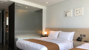 A hotel room with a large bed, bedside tables, a lamp, and a wall-mounted phone. - Gangneung City Hotel (Gangneung)
