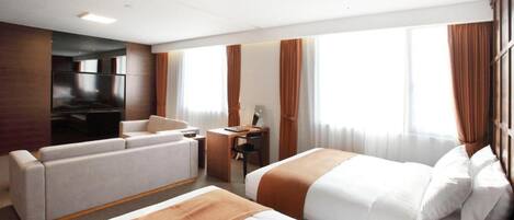 Habitación de hotel con dos camas, un sofá, un escritorio y una televisión.