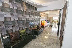A modern interior with a patterned wall, a leather sofa with colorful cushions, and a globe on a small table. - Garden House 152 (Tainan)
