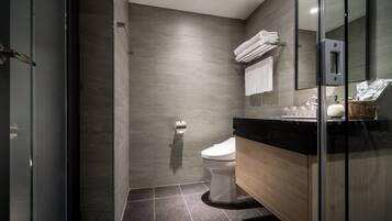 A modern bathroom with a glass shower enclosure, a toilet, and a vanity with a mirror.