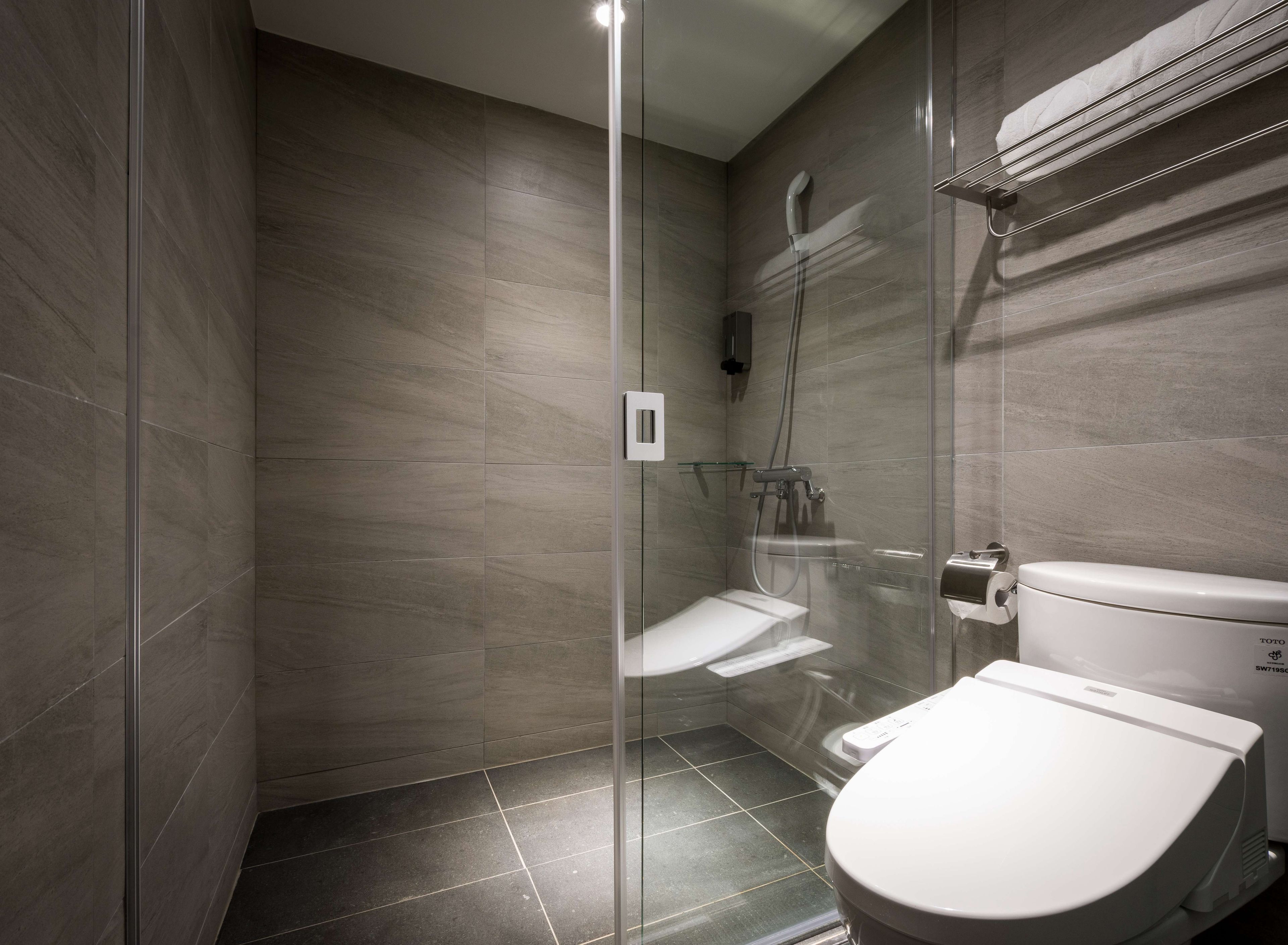 Un baño moderno con ducha de vidrio, inodoro y barra para toallas.