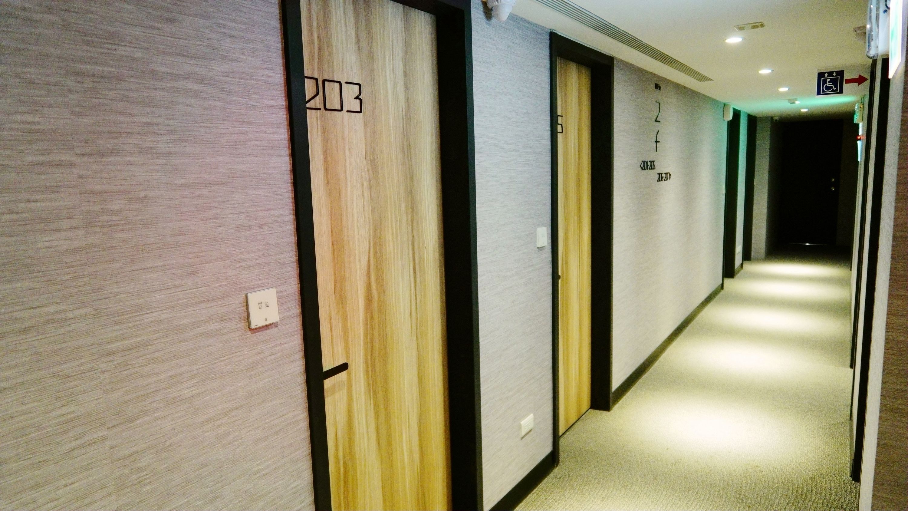 Pasillo de hotel con puertas de madera numeradas 203, 204 y 205.